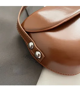 Détail de la texture du cuir marron avec des coutures précises et des rivets argentés