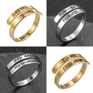 Detailed view of stainless steel open rings with engraved motivational quotes in gold and silver