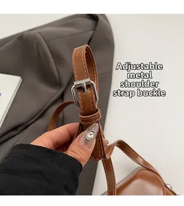 Détail de la bandoulière réglable en cuir avec boucle argentée sur un sac marron