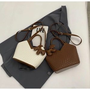 Flachbild von gewebten Ledereimertaschen in Creme und Braun mit Bärenanhängern