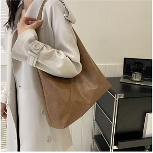 Close-up of brown vintage leather tote bag with vertical stitching shown on model