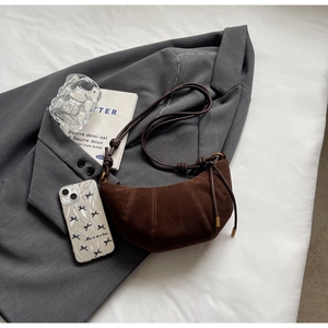 Detailed view of dark brown suede crescent bag featuring quilted sections and knot strap