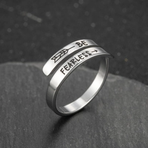Macro shot of stainless steel ring engraved with BE FEARLESS text on stone surface