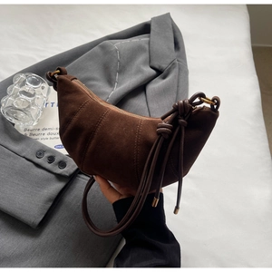 Detail of a brown suede croissant bag with vertical quilting and knotted shoulder strap
