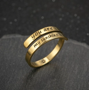 Detail of engraved you are my sunshine text and sun icon on golden stainless steel ring