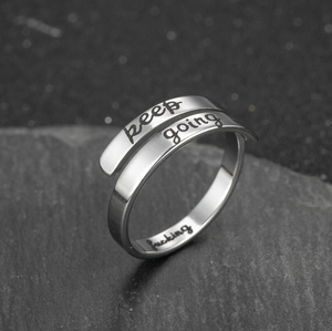 Detailed macro shot of vintage stainless steel ring with keep going engraved text
