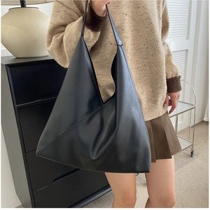 Detailed side view of black soft leather tote bag showing slouchy shape and wide strap