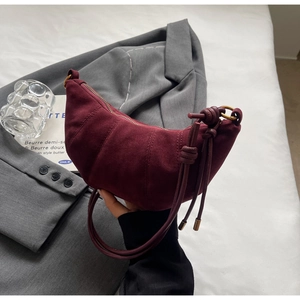 Detail of burgundy suede dumpling bag featuring vertical quilting and leather drawstring