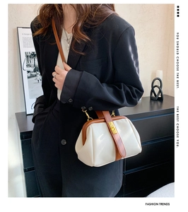 Detail view of vintage white doctor bag with brown leather trim and gold twist lock