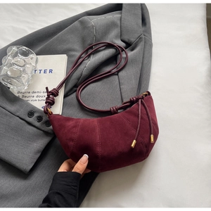Detail view of burgundy croissant bag featuring premium matte texture and pleated stitching
