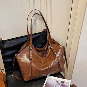 Borsa tote vintage in pelle sintetica marrone con tracolla su una sedia di pelle nera