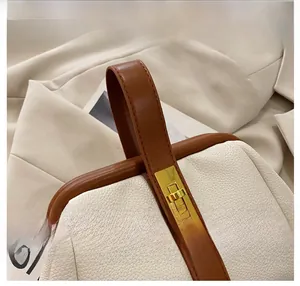 Close-up of beige lychee grain leather bag with brown handle and gold metal lock