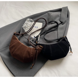 Detail view of coffee brown and black suede croissant bags on a grey blazer garment