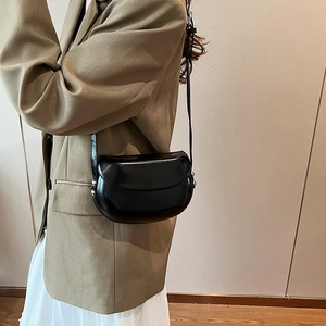 Détail d'un sac besace minimaliste en cuir noir avec des ornements en métal argenté