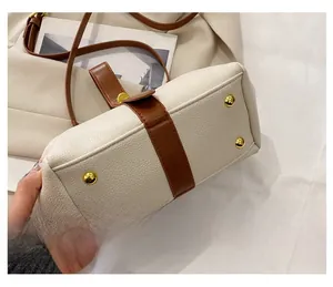 Detail view of the beige shell bag bottom featuring four golden metal studs for protection