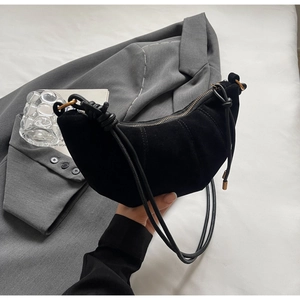 Close-up of matte black crescent bag with elegant knotted leather strap and metal zipper