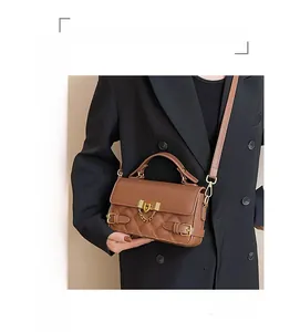 Close-up of brown quilted crossbody bag featuring gold metal lock and chain details