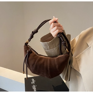 Detail of the knotted shoulder strap on a retro dark brown suede croissant bag