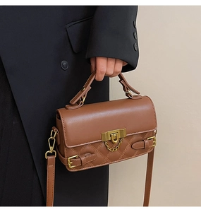 Detail shot of brown quilted crossbody bag with gold chain and metal buckle closure