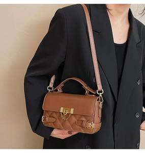 Detail of brown quilted leather handbag with gold chain lock on black blazer model