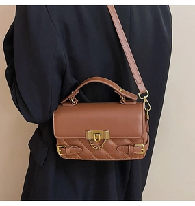 Detailed view of brown quilted crossbody bag with gold hardware on a model jacket