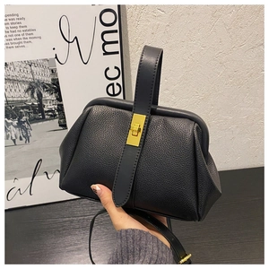 Detail of black lychee grain leather shell bag with gold twist lock for daily use