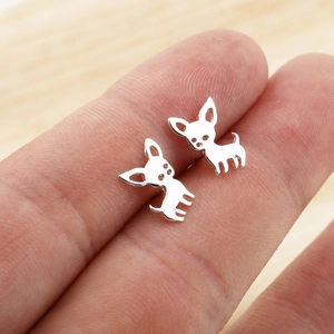 Macro shot showing the size of silver puppy-shaped stud earrings held between fingers