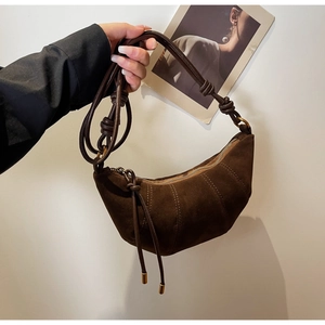 Detailed macro view of dark brown suede crescent bag featuring knot decor and tassels