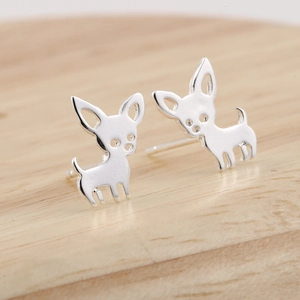 Macro shot of silver chihuahua stud earrings on a natural wood texture background