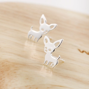 Detail view of silver-tone puppy-shaped earrings on a light wooden background