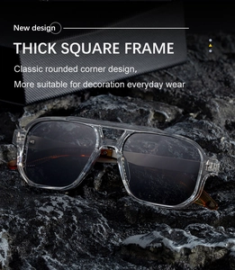 Detail view of thick transparent grey square frame sunglasses on dark rocky background