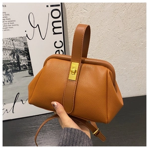 Close-up of caramel pebble leather handbag featuring a vintage gold twist lock and handle