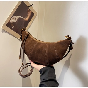 Detail of dark brown matte suede croissant bag showing curved stitching and zipper
