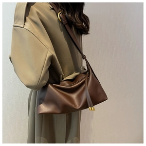 Detail view of large dark brown leather tote bag with adjustable strap and metal hardware