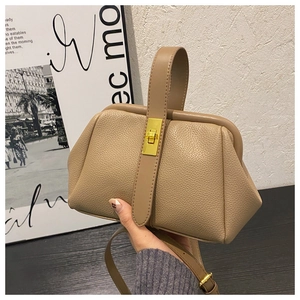 Detail of tan pebble leather bag with golden metal clasp and adjustable strap
