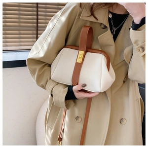 Detail of retro shell bag with cream leather, brown straps and golden twist lock closure