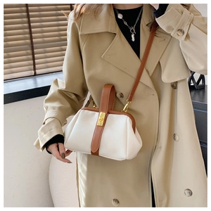 Close-up of white lychee leather handbag with brown trim and golden metal twist lock