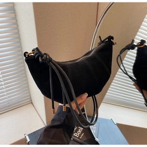 Close-up of black suede crescent bag showing stitching detail and silver zipper closure