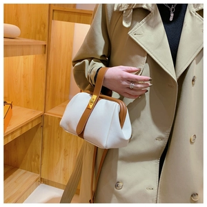 Close-up of white lychee leather texture and golden twist lock on a vintage handbag