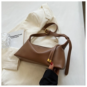 Detailed view of brown leather tote bag featuring gold hardware and fringe tassels