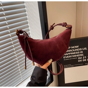 Close-up of burgundy frosted suede croissant bag with knotted strap and gold hardware