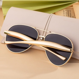 Classic gold pilot sunglasses detail with dark lenses on a cream leather pouch case