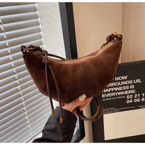Detail of dark brown suede croissant bag with knotted shoulder strap and gold hardware