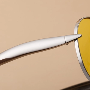 Macro view of silver metal hinge and yellow aviator lenses on fashion sunglasses