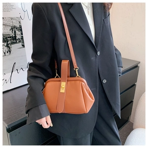 Close-up of vintage brown doctor bag with lychee texture and gold buckle on a model