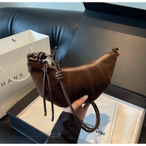 Detailed view of dark brown suede crescent bag with signature knot and vertical stitching
