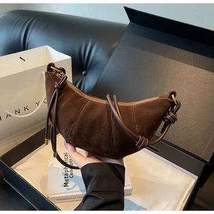 Detail of dark brown suede croissant bag with hand-held knot strap and gold ring hardware