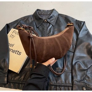 Detail of dark brown suede crescent bag with quilted stitching and leather strap