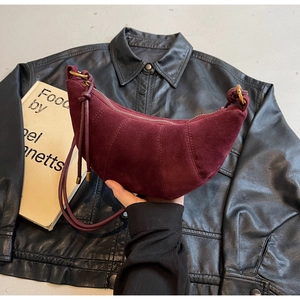 Close-up of burgundy frosted suede crescent bag with stitching detail and gold hardware