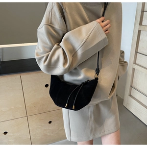 Detail of black crescent crossbody bag with vertical stitching and gold hardware finish